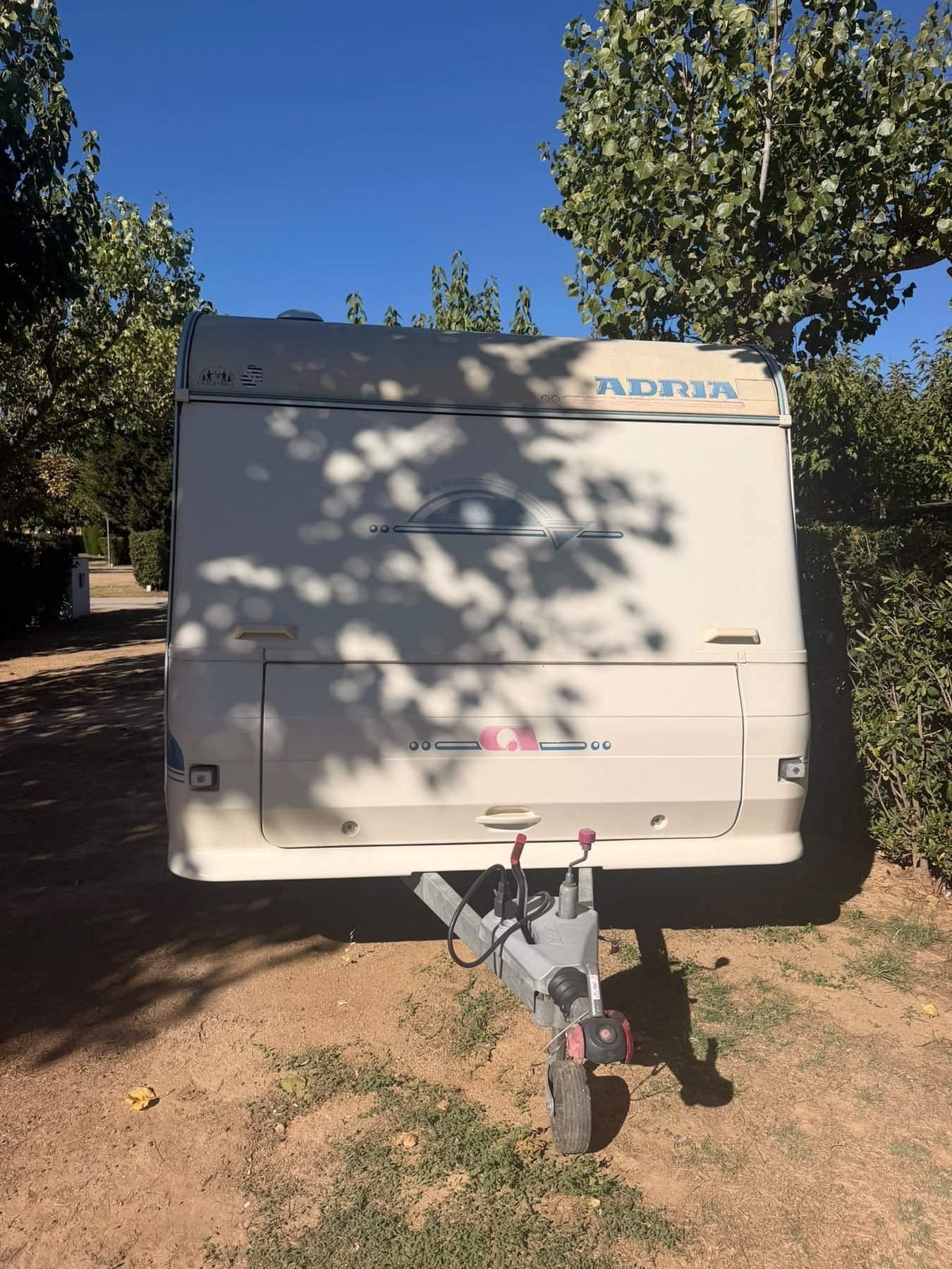 Adria caravan on its jockey wheel on a shaded pitch