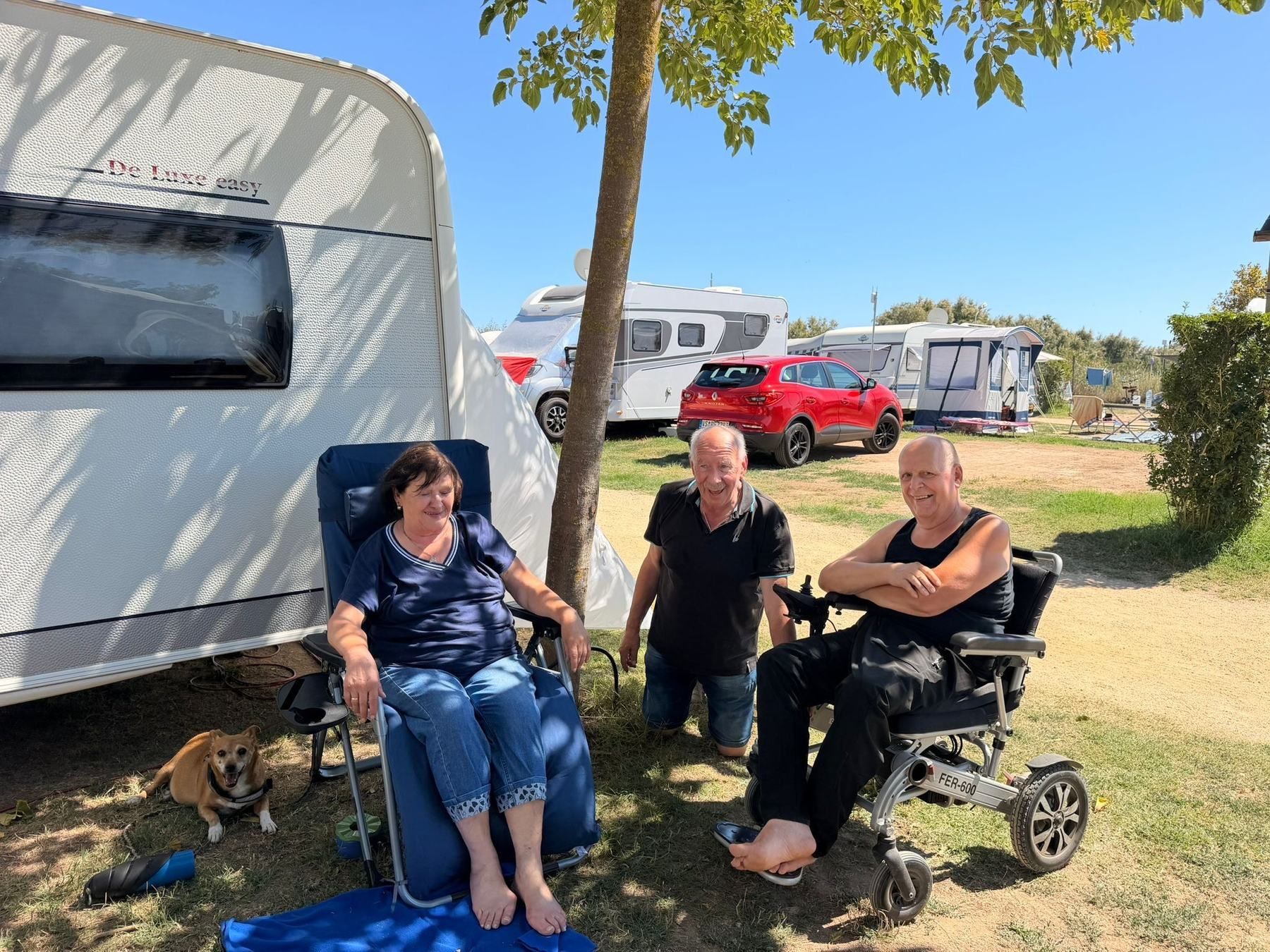 Three caravan owners relaxing in the shade beside their caravan