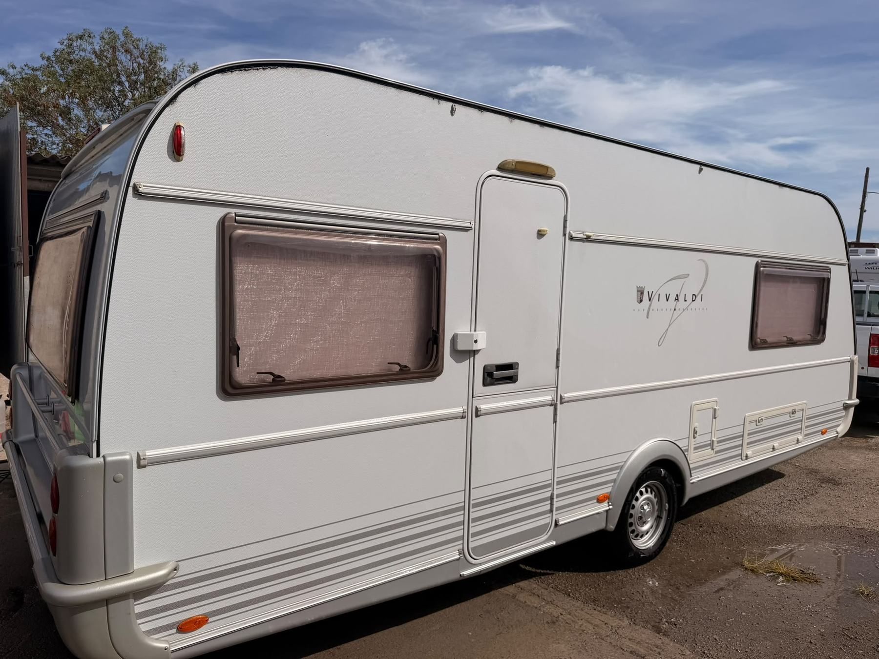 White Vivaldi caravan parked in a yard, door side view