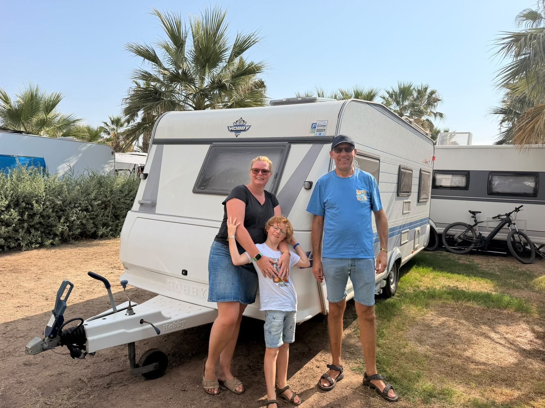 Family standing in front of their caravan on the pitch