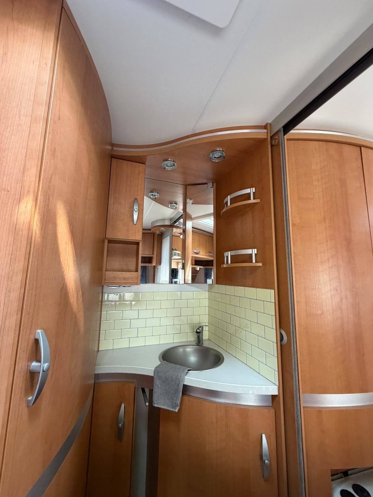 Caravan washroom with a corner sink and tiled splashback