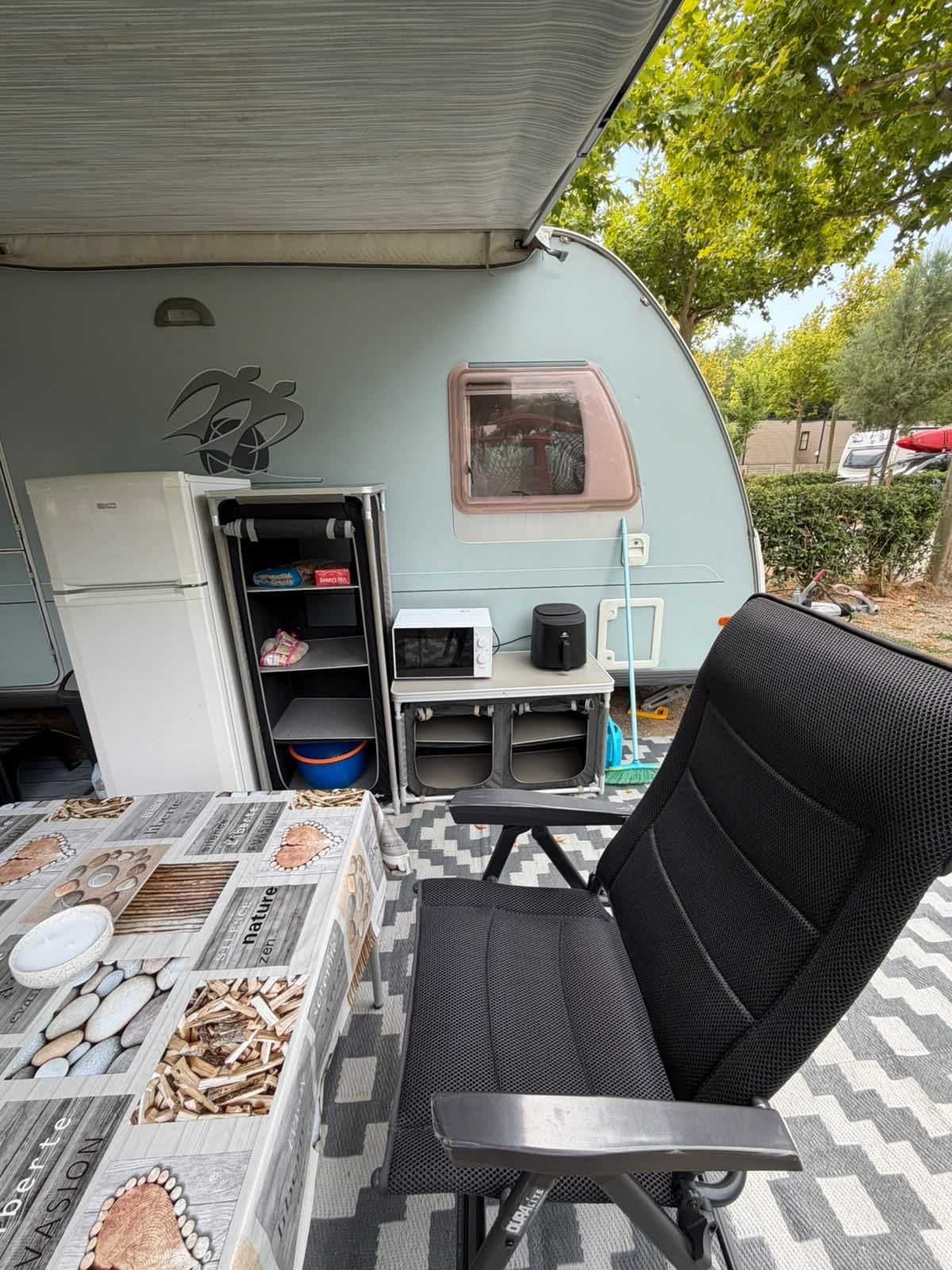Awning set up with a fridge, kitchen unit, table and chairs