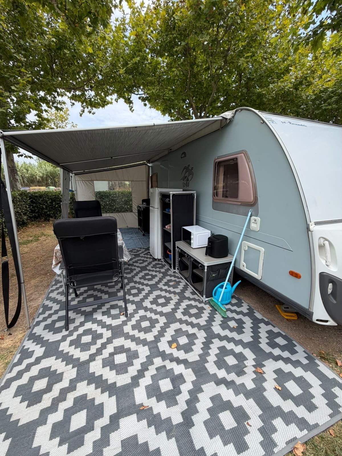 Caravan awning with a patterned groundsheet, chair and kitchen unit
