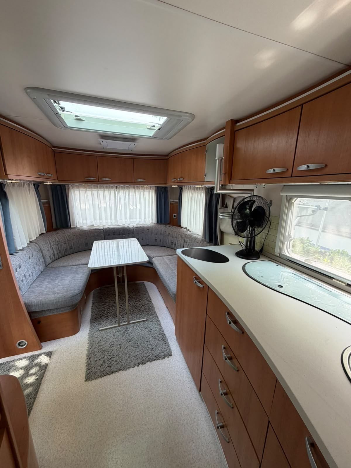 Caravan dinette and kitchen with a fan on the worktop