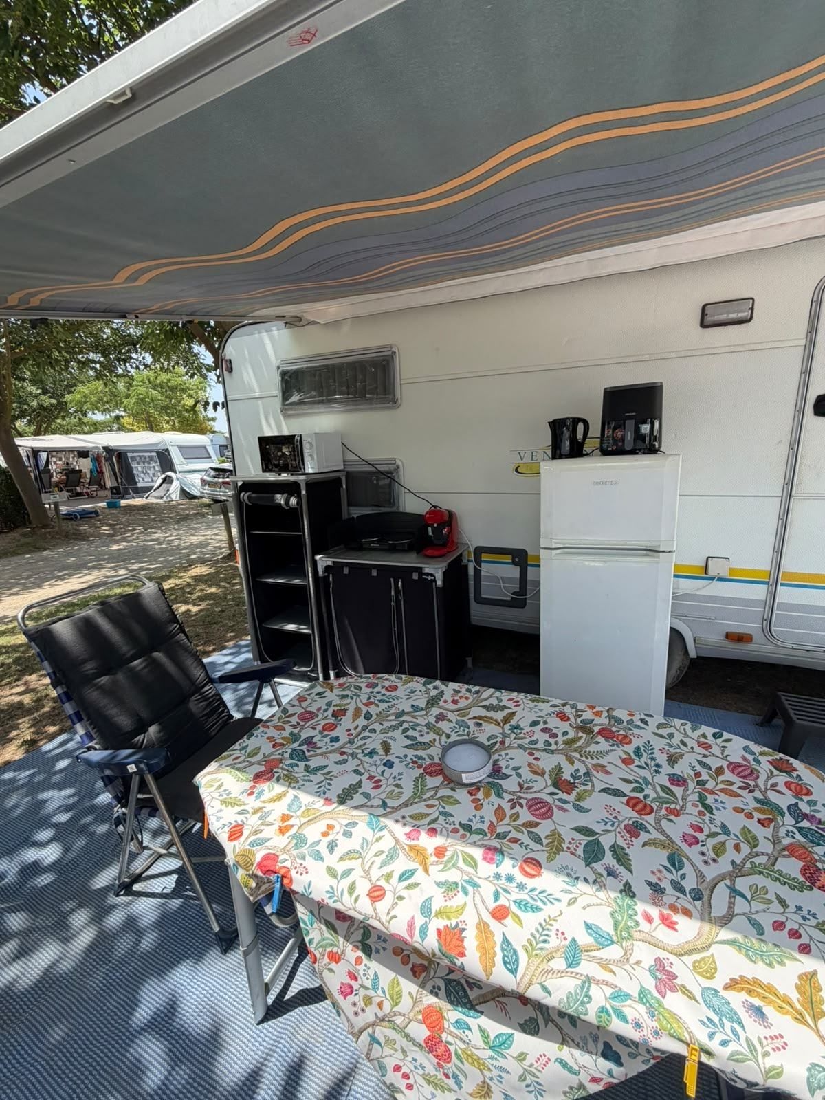 Awning with a floral table cloth, chairs and kitchen unit