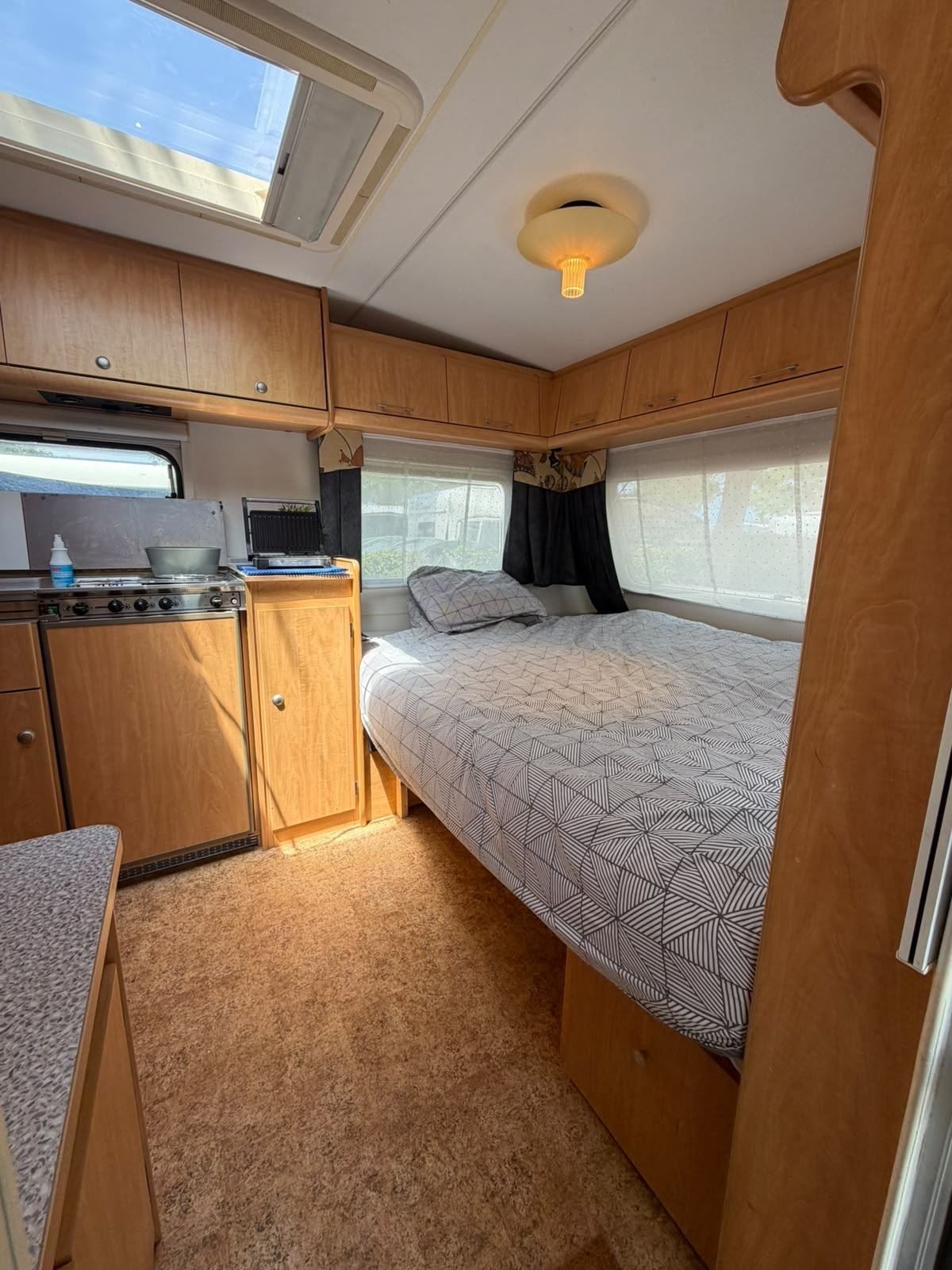 Caravan bedroom with a skylight and the kitchen alongside
