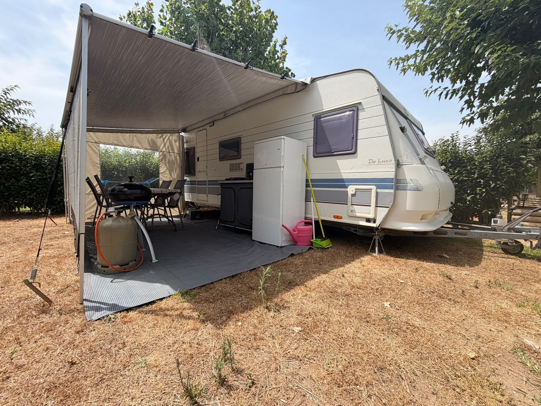 Caravan with an awning, fridge and dining set on a dry pitch
