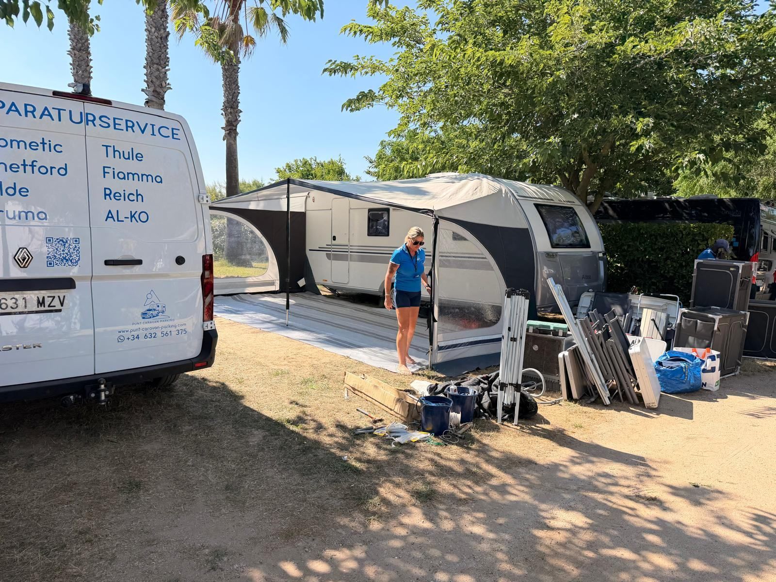 Service van and caravan with awning frames and gear laid out on the pitch