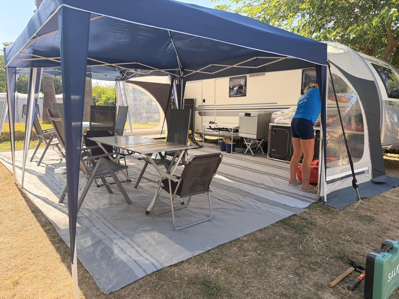 Gazebo with table and chairs set up beside a caravan