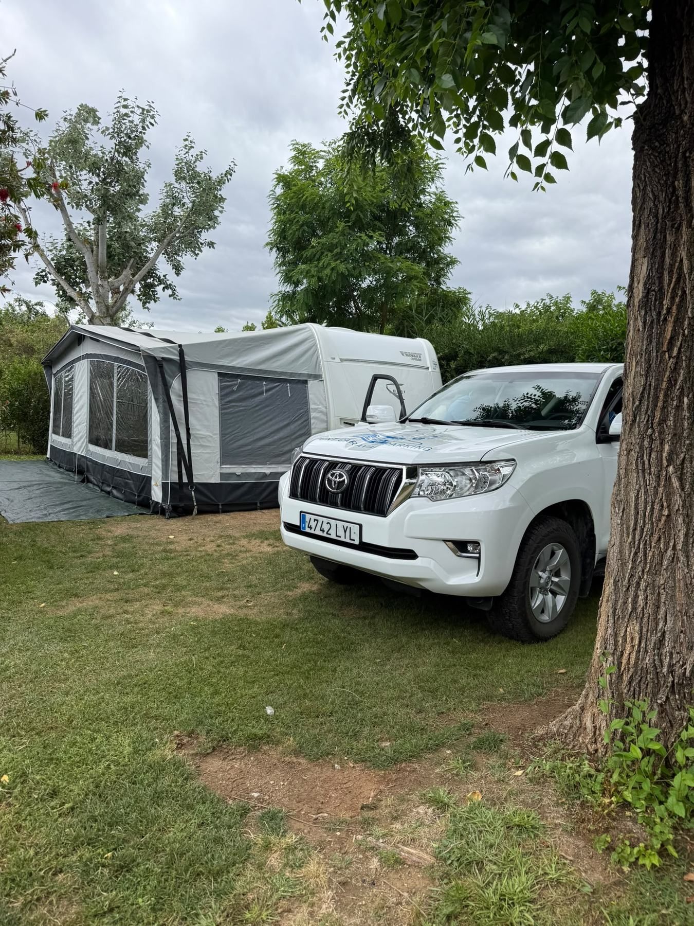 Toyota 4x4 parked beside a caravan with its awning up on a grassy pitch