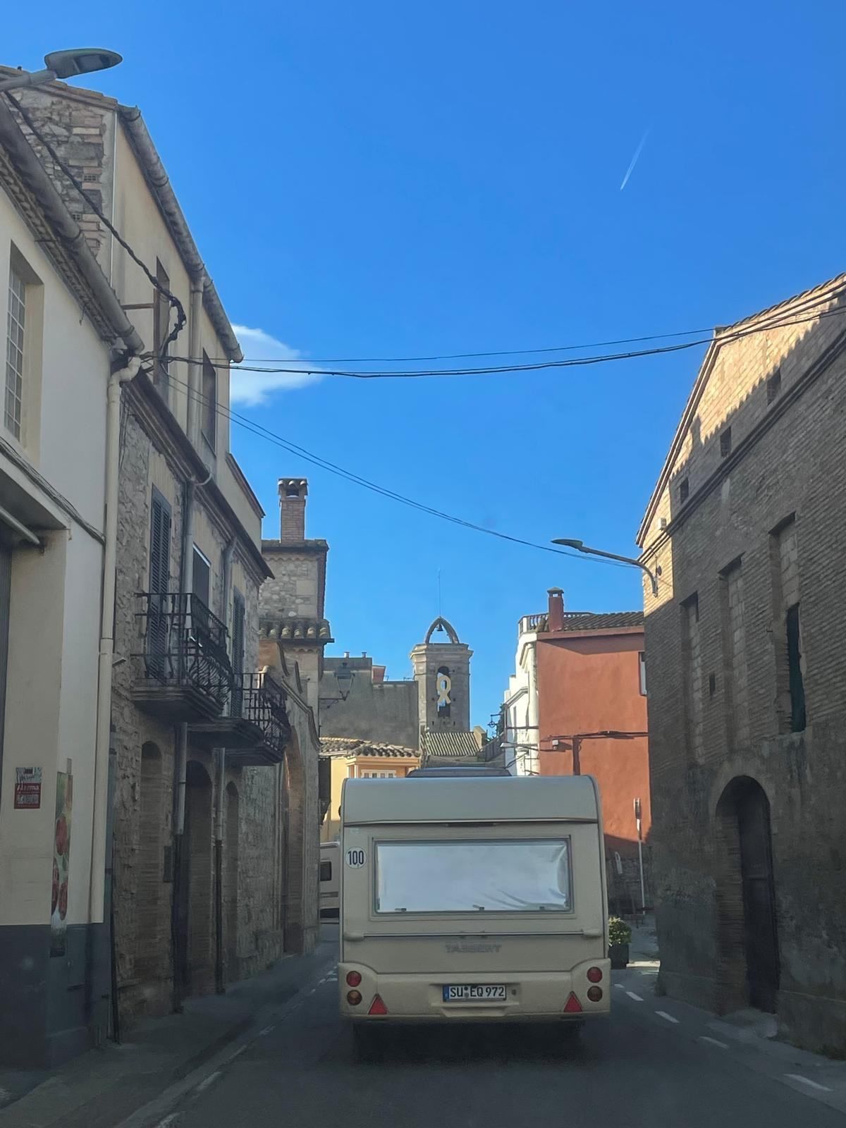 Caravan being towed through a narrow village street