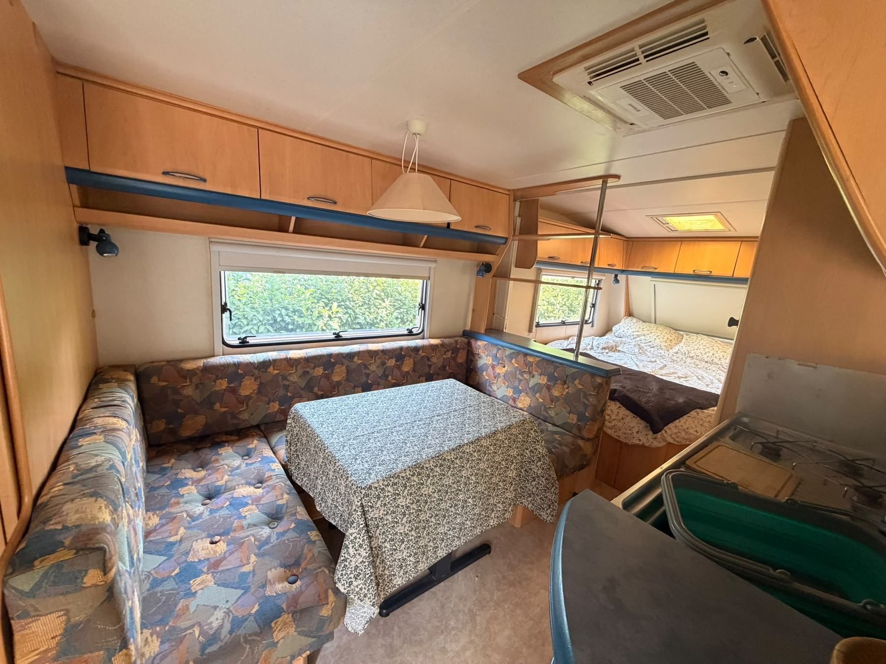 Caravan dinette with a table, seating and a bed at the far end