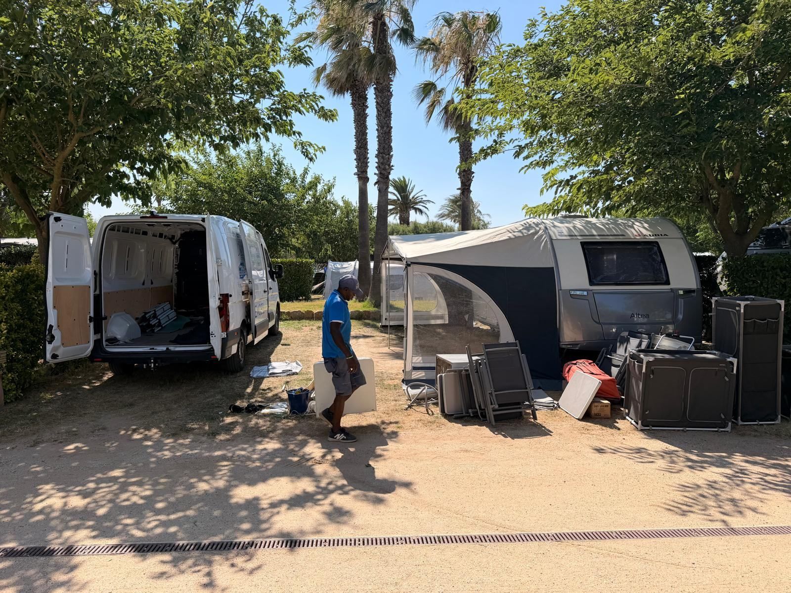 Team member unloading awning parts from a van beside a caravan on its pitch