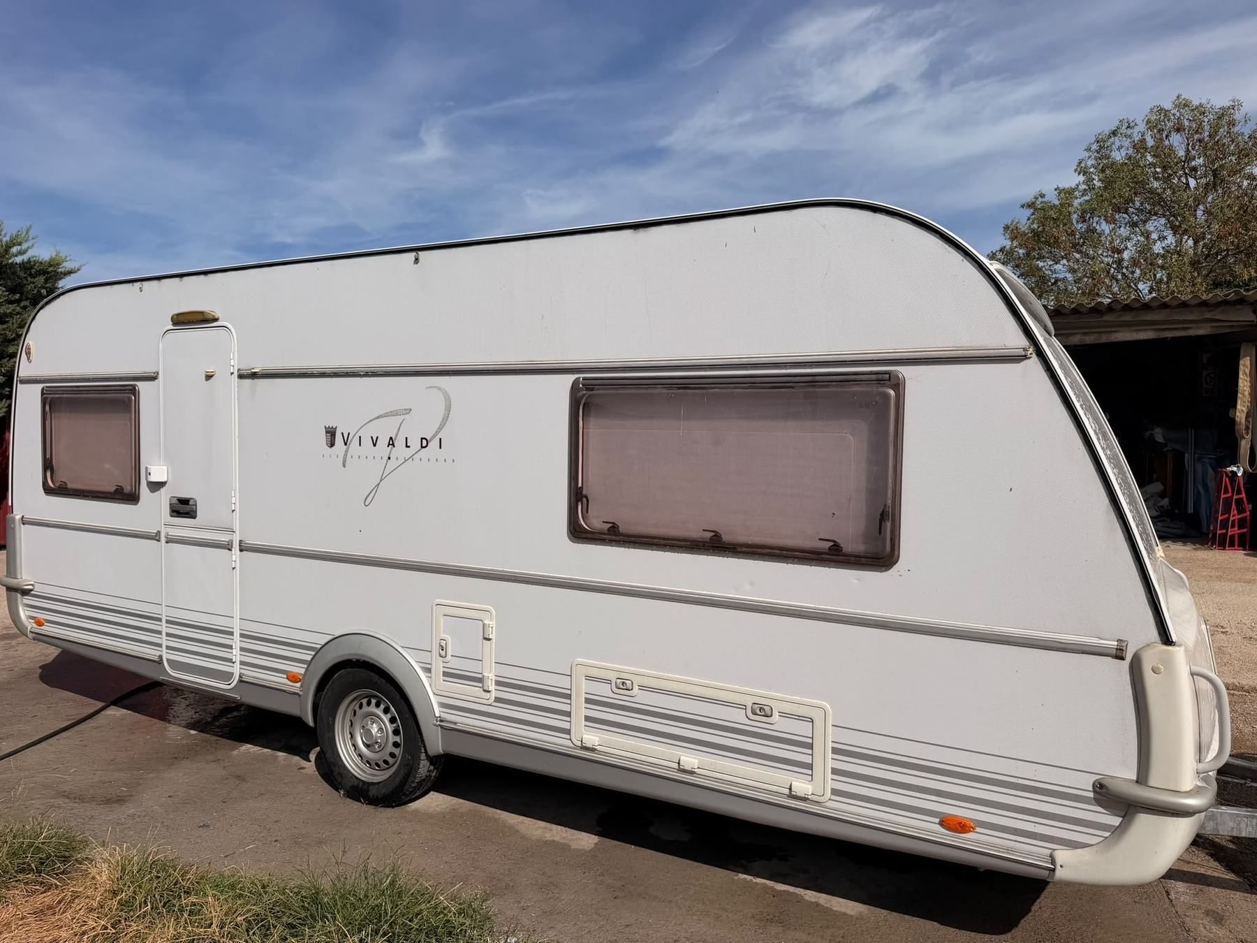 White Vivaldi caravan standing in a sunny yard, side view